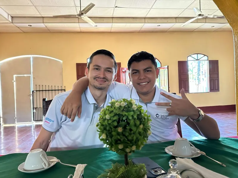 Erick y Erick abrazados y sonriendo en la oficina